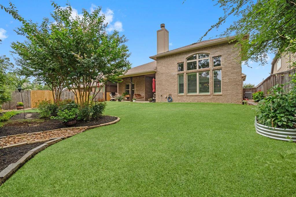 Enjoy the covered patio with a stained tongue-and-groove ceiling, surrounded by lush landscaping and pavers, with plenty of space for a future pool.