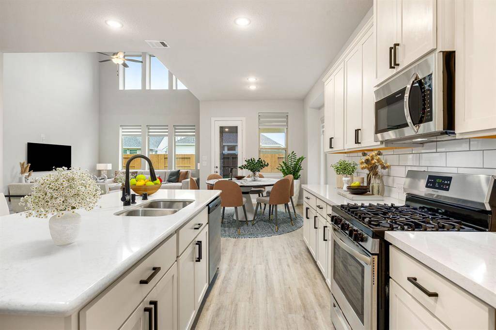 Prepare to be inspired by this beautifully maintained kitchen—both stylish and highly functional. Perfectly positioned with direct access to the breakfast area and living room, it’s designed to keep everyone connected, whether you're entertaining or enjoying a quiet morning. The light, airy cabinetry enhances the spacious feel, while the rich wood flooring adds a touch of warmth. A large center island with a breakfast bar offers plenty of room for casual dining or gathering, and the walk-in pantry, along wi