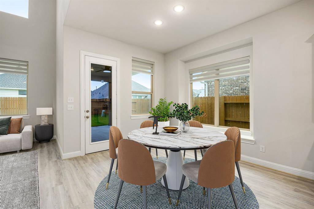 This lovely breakfast area is perfect for starting the day out on the right foot.  This space showcases neutral paint, high ceilings, recessed lighting, large window seat adding to the ample natural light in the kitchen, and wood flooring.