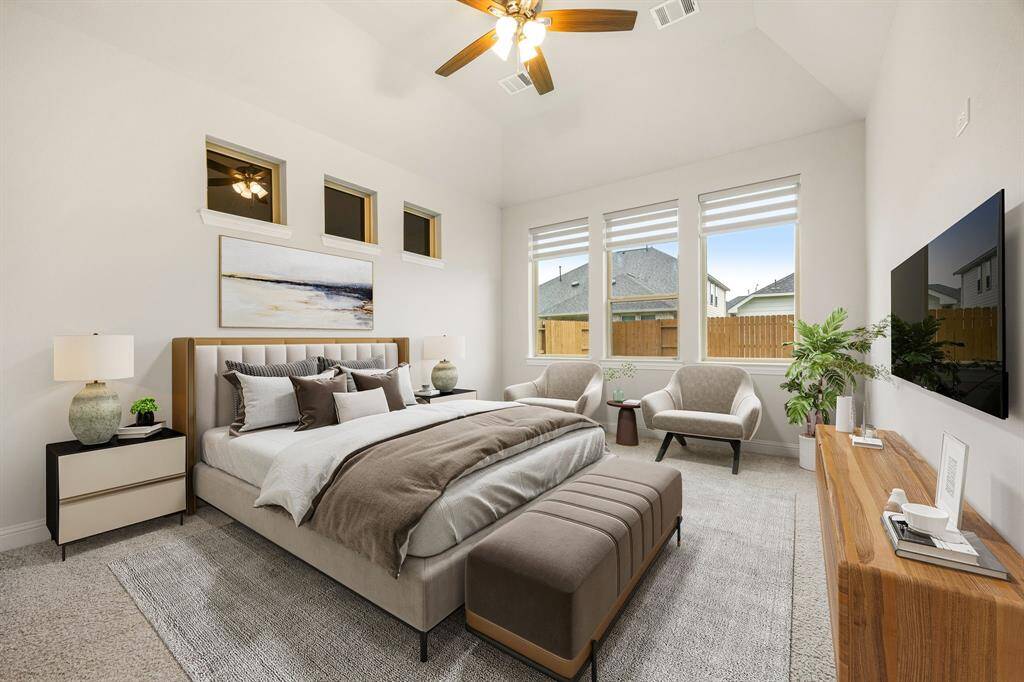 Welcome to your own private retreat—this stunning primary suite offers the perfect blend of comfort and elegance. Step into a spacious bedroom adorned with soft, plush carpeting, warm neutral tones, and elevated ceilings that enhance the airy feel. Large windows with stylish blinds invite in an abundance of natural light, creating a bright and serene atmosphere. A ceiling fan with lighting adds both function and charm, while the generous layout includes a cozy nook perfect for a reading chair.