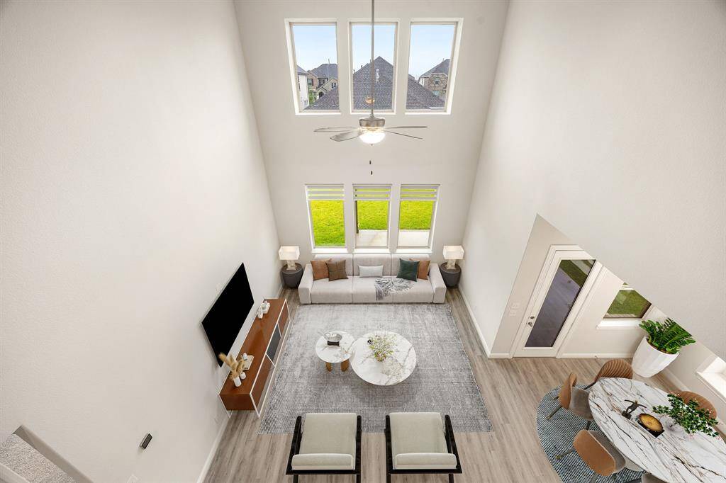 Soaring ceilings and abundant natural light define this stunning two-story living space. Expansive windows offer picturesque views and fill the room with warmth, while the open layout seamlessly connects to the dining area and backyard access, creating the perfect flow for entertaining or relaxing at home. Elegant flooring and neutral tones provide a versatile canvas for your personal style.