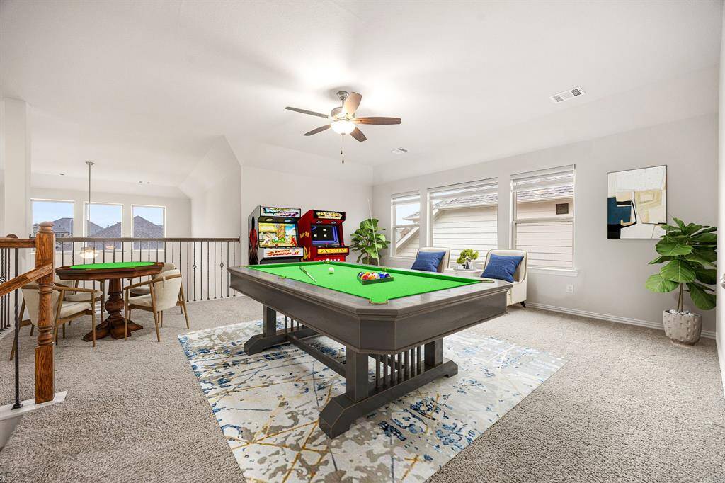 Step into the ultimate entertaining space with this incredible upstairs game room! Whether you're envisioning the perfect teen retreat or a sophisticated adult hangout, this versatile area is ready for fun—think pool table, big screen TVs, and more. Enjoy the comfort of plush carpeting, soaring ceilings, and a rich, dark-stained ceiling fan. Large windows with privacy blinds let in natural light while maintaining a cozy, private feel, all accented by elegant neutral tones to suit any style.