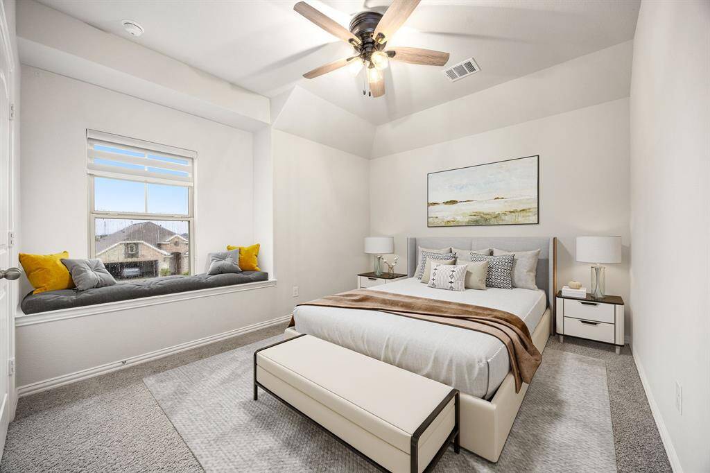 Secondary bedroom features plush carpet, neutral paint, dark stained ceiling fan with lighting and a gorgeous window seat with privacy blinds.