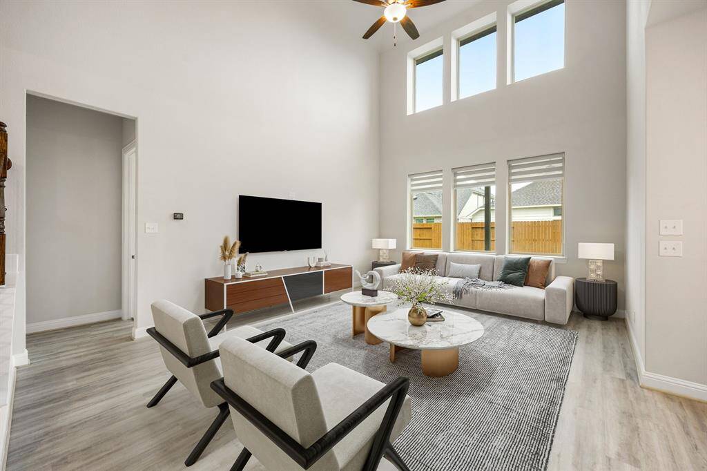 Whether you're hosting a lively get-together or enjoying a quiet evening at home, the generous layout easily adapts to your lifestyle. Rich hardwood floors, dramatic ceilings, and expansive windows fill the space with warmth and natural light. Recessed lighting adds a sleek, modern touch, while easy access to the stunning kitchen makes both entertaining and everyday living a breeze.