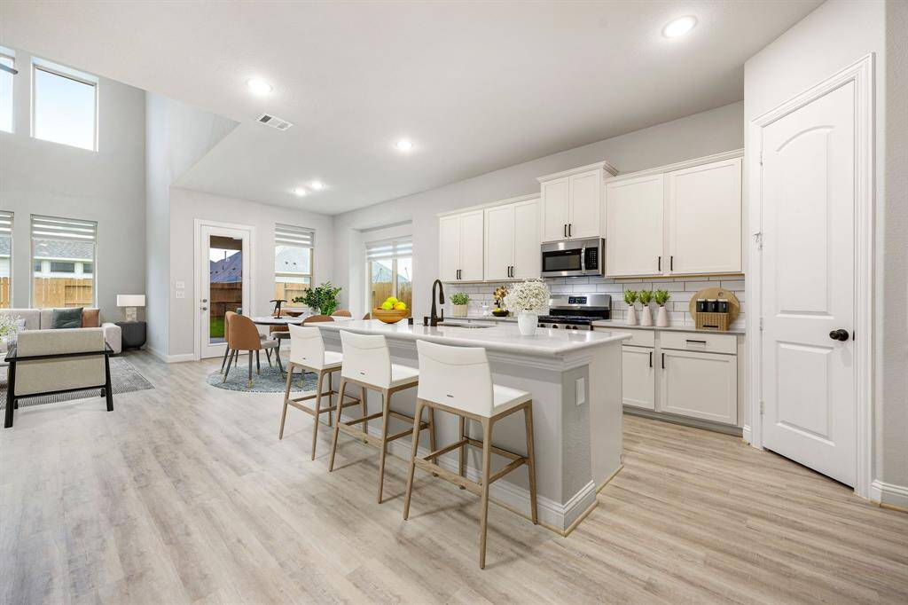 Designed with both style and function in mind, the kitchen effortlessly flows into the breakfast room, casual dining area, and living space, making entertaining seamless. Gleaming wood floors, crisp, bright cabinetry, and an oversized island with a breakfast bar enhance the sense of space and light. A spacious walk-in pantry and generous counter space provide all the room you need for cooking, hosting, or simply enjoying everyday moments in a beautifully open setting.