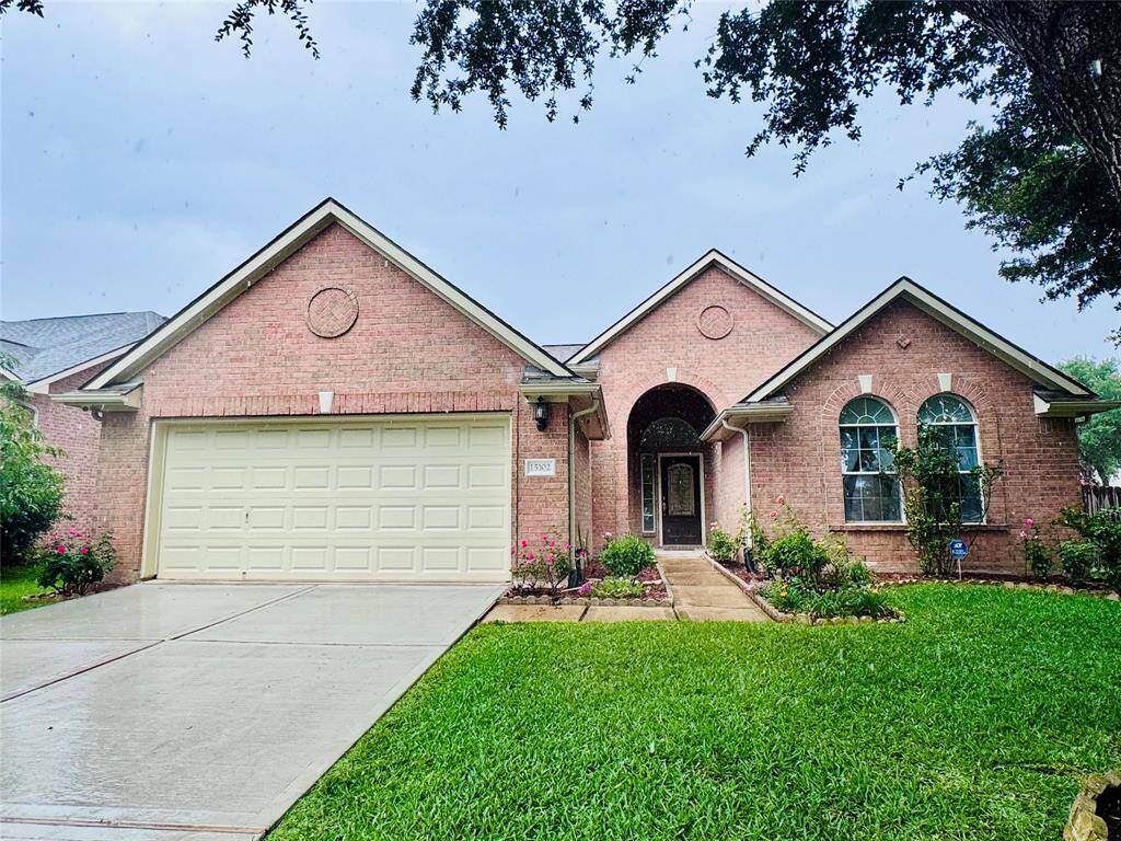 This charming brick home features a two-car garage, a well-maintained lawn, and a welcoming front entrance with arched windows. Ideal for comfortable family living.