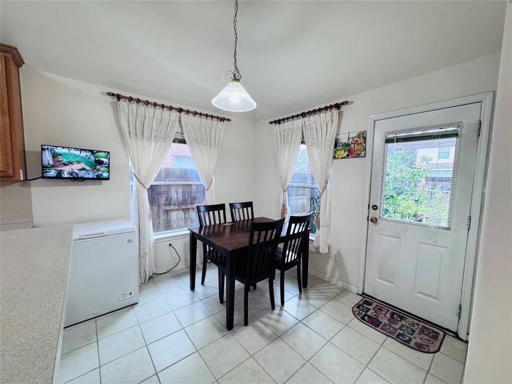 Bright breakfast area with large windows, tiled floor, door leading to the backyard, creating a welcoming space for meals and gatherings.