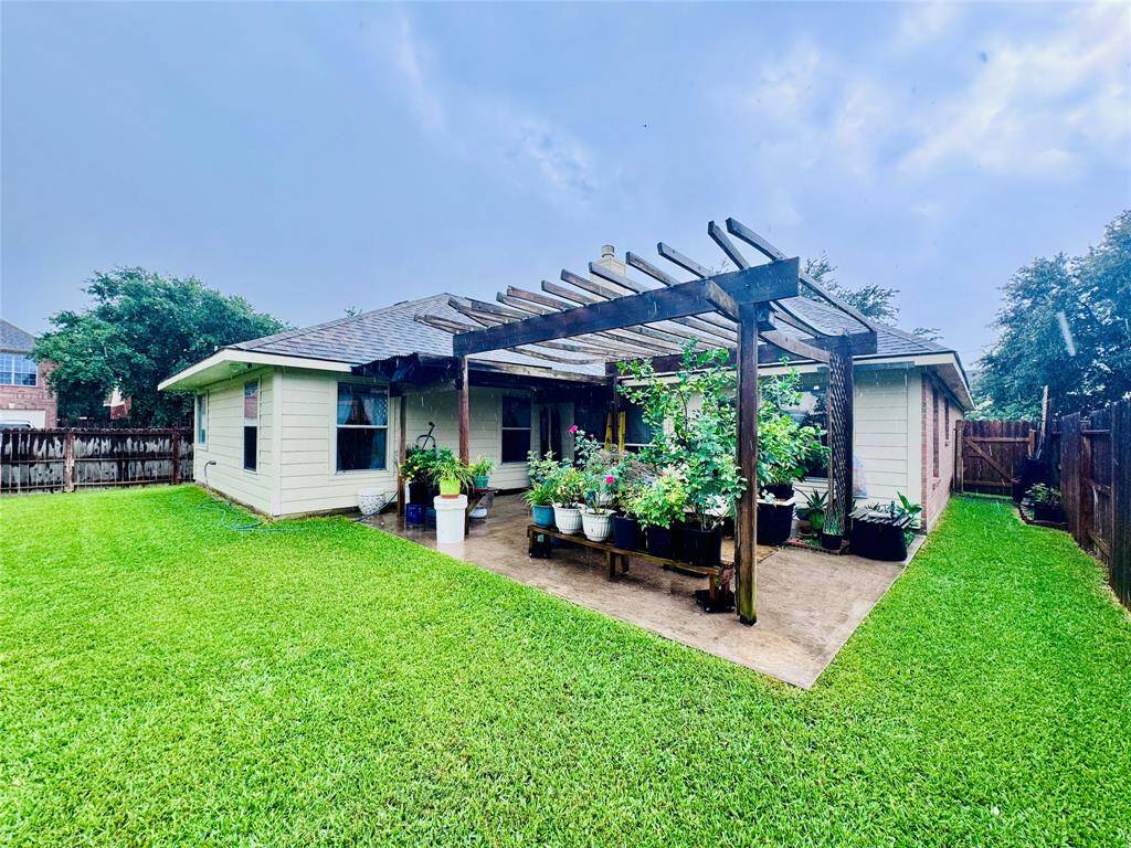 Charming backyard with a lush green lawn and a wooden pergola, perfect for outdoor relaxation. The area is well-maintained, offering ample space for gardening and leisure activities.