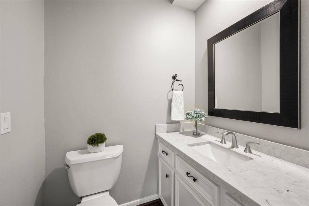 Updated powder bath includes toilet, flooring, counters, sink, faucets and mirror.