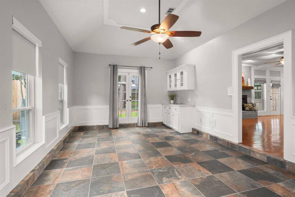 Downstairs game room is filled with natural light from wall-to-wall windows and features a stylish wet bar—perfect for entertaining. French doors open directly to the backyard, blending indoor and outdoor living.
