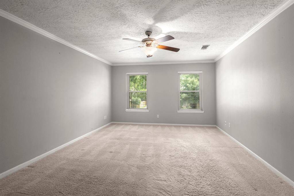 Plush carpet with thick padding, a ceiling fan for year-round comfort, elegant crown molding, and a restful color palette all come together to make this primary suite a true retreat.