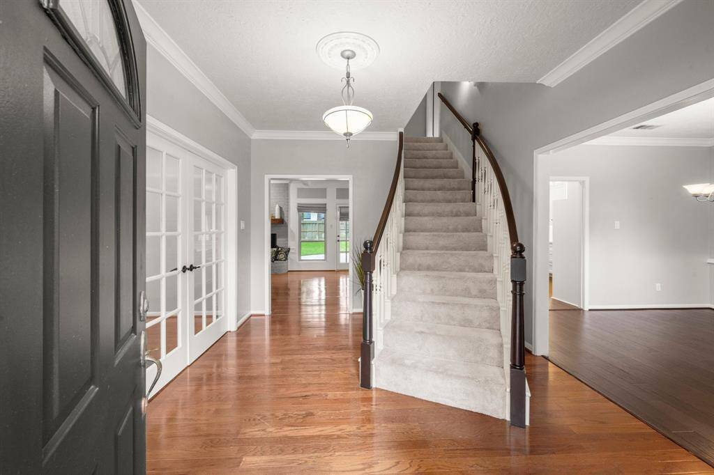 Step inside to warm wood floors and a welcoming layout with sightlines that draw you toward the bright windows and the graceful curve of the staircase.