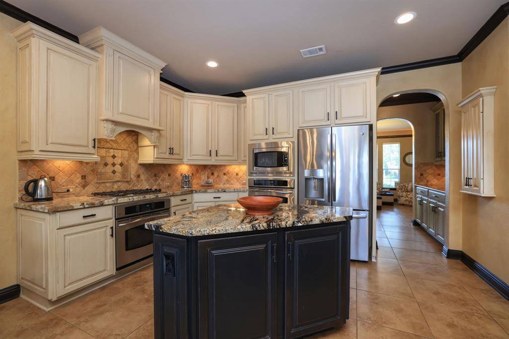 Exotic level granite with bullnose edge. Five burner gas cooktop. Tumbled marble backsplash and soft creak painted cabinets with cabinets pulls.