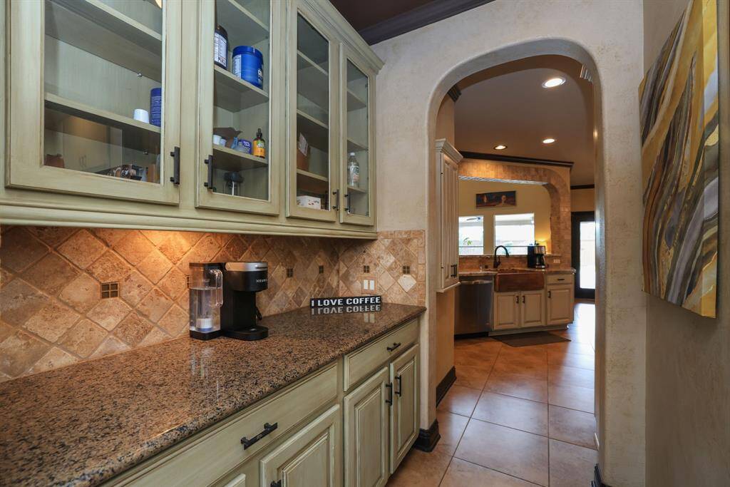 Customized with paint technique cabinetry, granite tops, under cabinet lighgting and glass display fronts. Door to laundry across from pantry