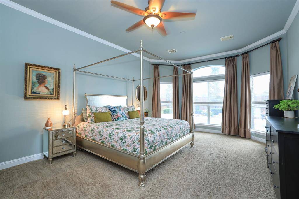 Primary bedroom with soft paint tones, custom draperies and crown molding.