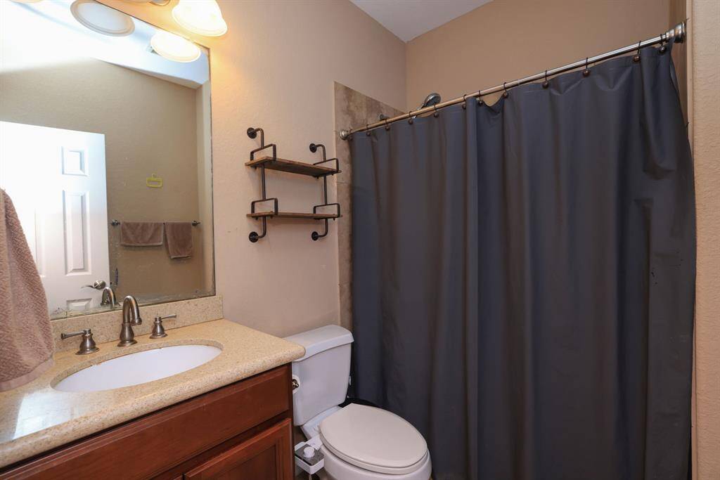 Full bath with shower/tub combo and cherry wood cabinets and granite counters.