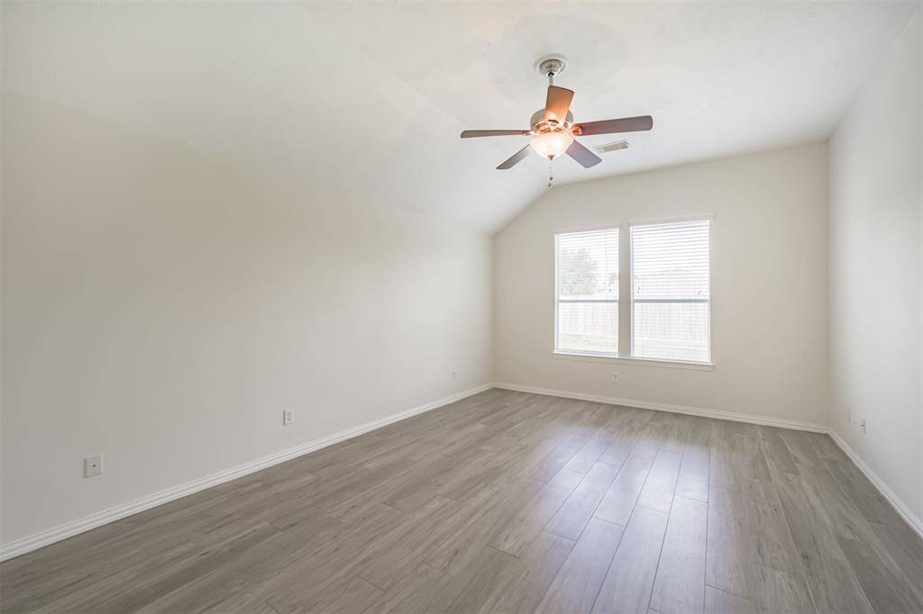 Expansive primary bedroom with ceiling fan and ample natural light.