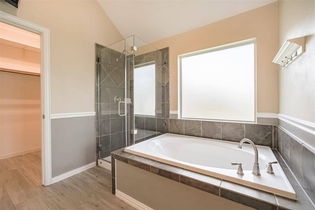 Tub and shower with framless glass door  in primary bathroom.