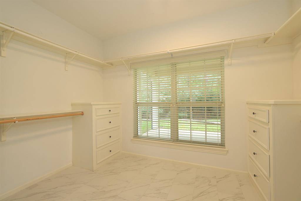 The primary closet features built-ins with upper and lower hanging rods, offering smart storage and organization. Spacious and well-designed, it provides plenty of room for your wardrobe and accessories.
