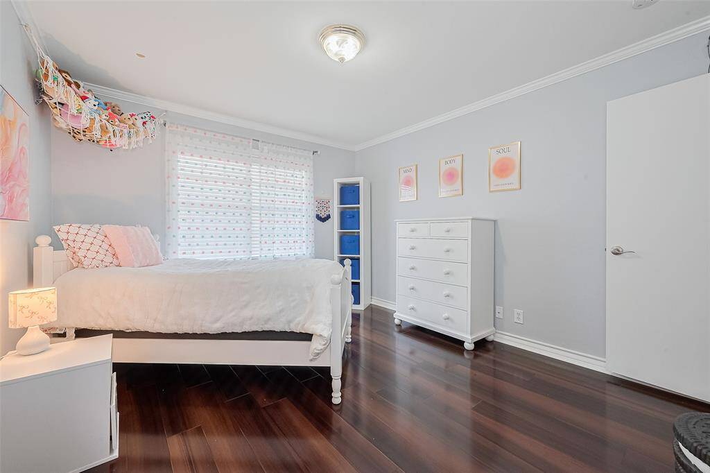 This inviting secondary bedroom offers a cheerful space with beautiful new flooring and soft natural light streaming through a large window. Light gray walls with crisp white trim create a calming atmosphere, perfect for a guest suite or home office. The room features ample space for furniture and storage, and the clean, neutral finishes make it move-in ready and easy to personalize.
