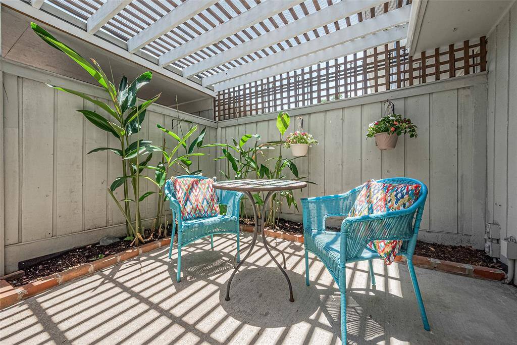 Step outside to your own tranquil outdoor retreat. This spacious, fully fenced private patio features a pergola-style cover that filters natural light beautifully while offering shade for relaxing or entertaining. Surrounded by tropical greenery and hanging plants, this low-maintenance space is perfect for morning coffee, evening cocktails, or container gardening.