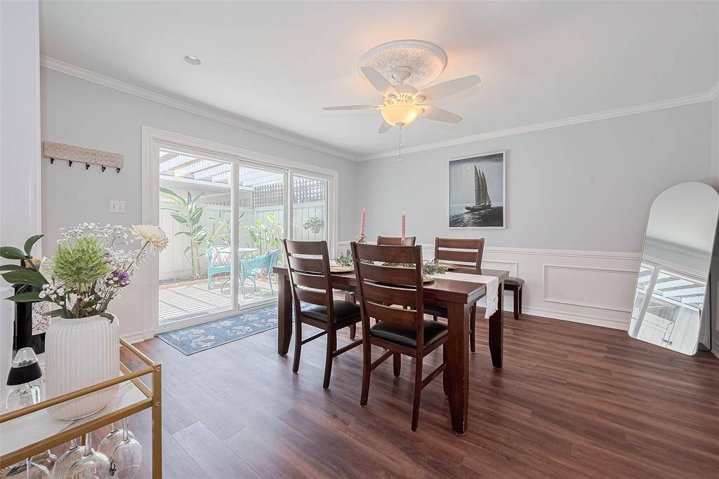 This beautiful dining room features rich luxury vinyl flooring, crown molding, with updated lighting. A built-in glass-front china cabinet adds charm and functionality, while the  updated glass doors open to a private patio, creating the perfect indoor-outdoor flow for entertaining. Just off the kitchen, this inviting space is ideal for both formal gatherings and everyday meals.