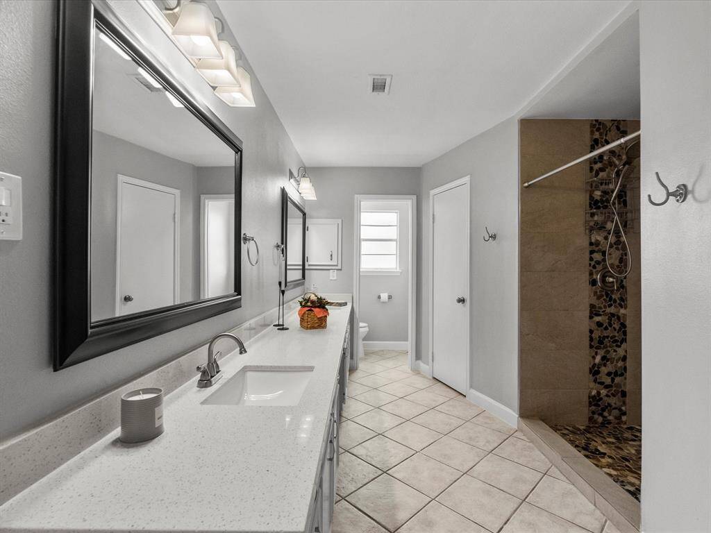 Luxurious primary bathroom featuring a sleek standing shower and dual closets for ample storage.
