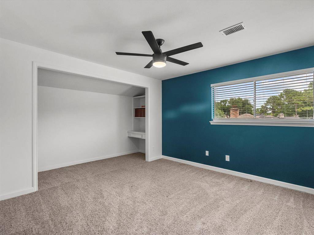 Spacious upstairs bedroom with cozy carpeting, a built-in nook, and abundant natural light through a large window.