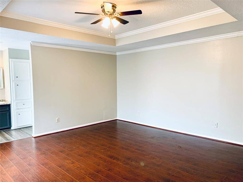 Primary bedroom has neutral paint with tray ceiling and ceiling fan!