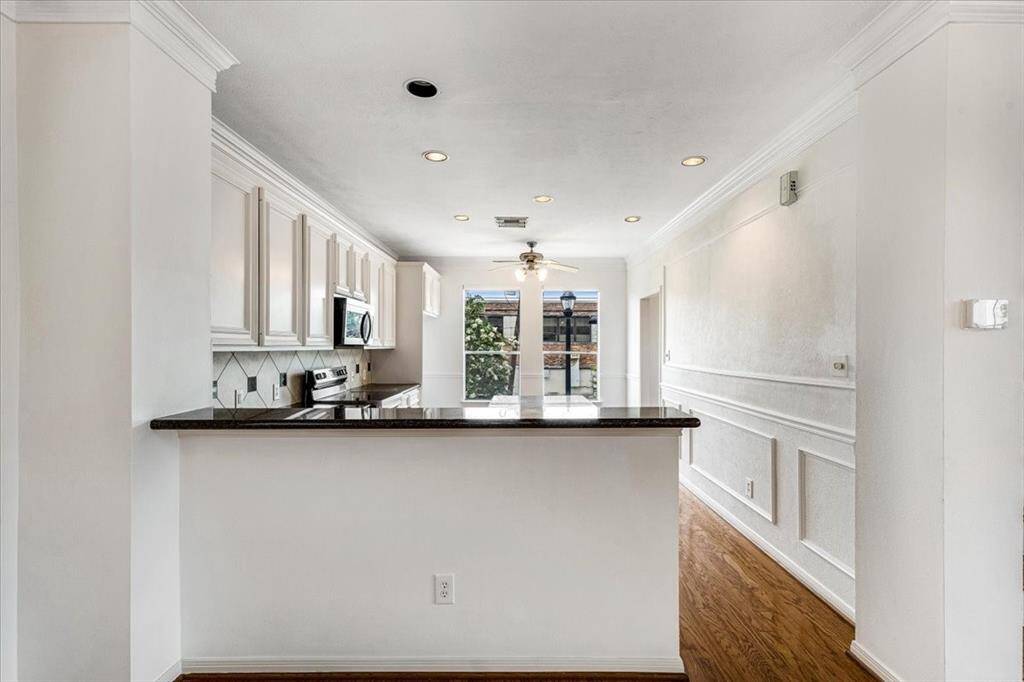 Bar-height pass-through overlooks the living space, while the kitchen opens up to a bright breakfast nook with large windows and a ceiling fan.