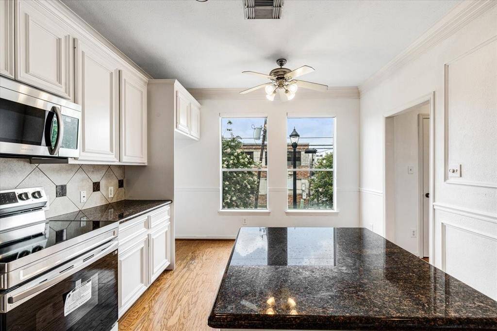 Bright and airy kitchen with an oversized window by the breakfast nook, detailed wainscoting, and space for a coffee bar or casual dining setup.