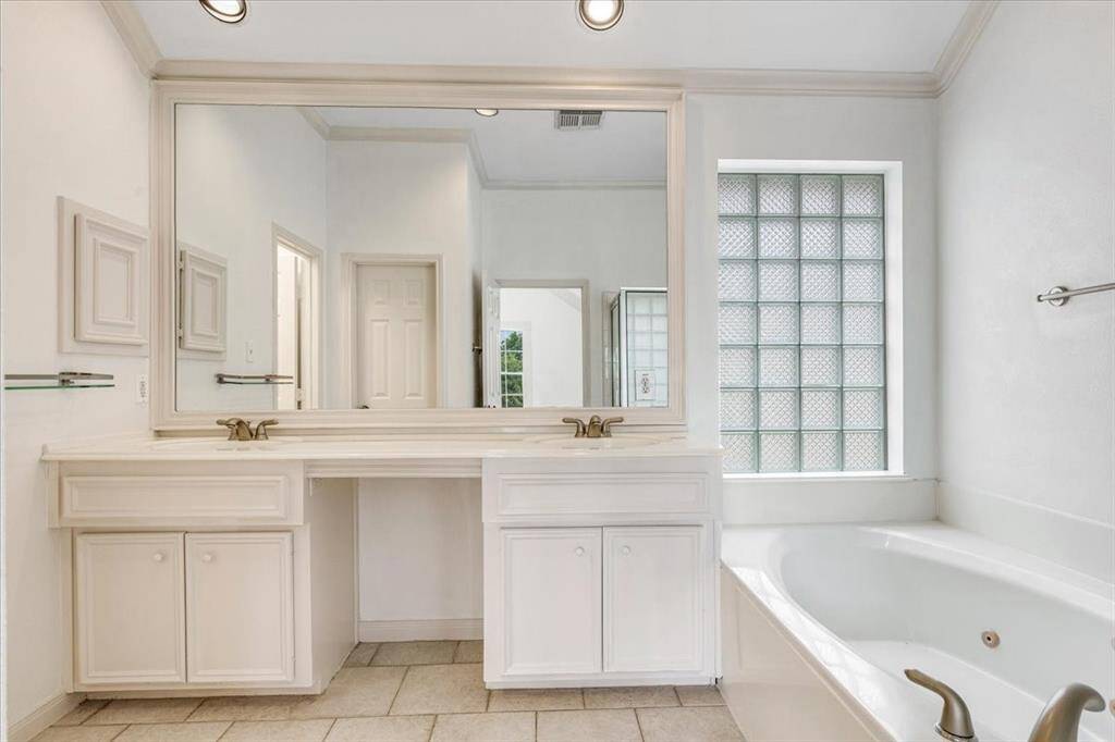 Relax in the garden-style jetted tub surrounded by classic tilework and illuminated by a decorative glass block window.