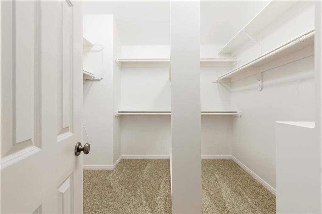 Expansive walk-in closet with dual hanging sections and shelving, providing generous space for clothing and storage.