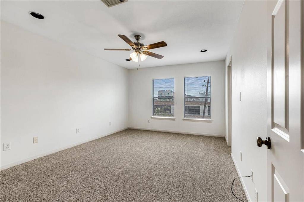 Third bedroom with plush carpet, ceiling fan, and front-facing windows offering plenty of natural light and views of the street below.