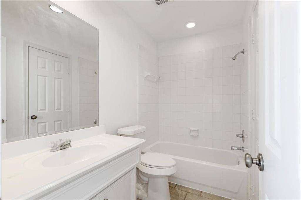 The ensuite full bath features a single vanity, overhead lighting, and a tub/shower combo with crisp white tile.