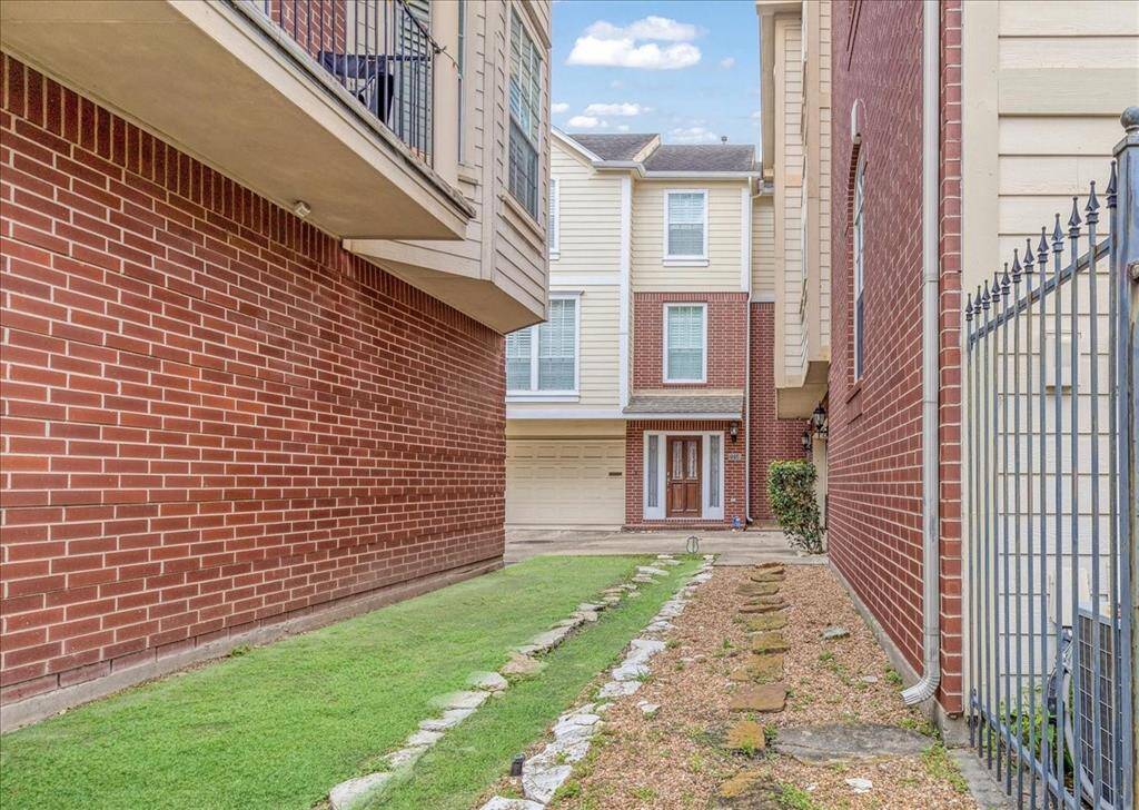 A charming front entry tucked between buildings with a dedicated walkway leading to the main patio. This small front space offers potential for a welcoming flower bed or decorative landscaping to add personal flair.