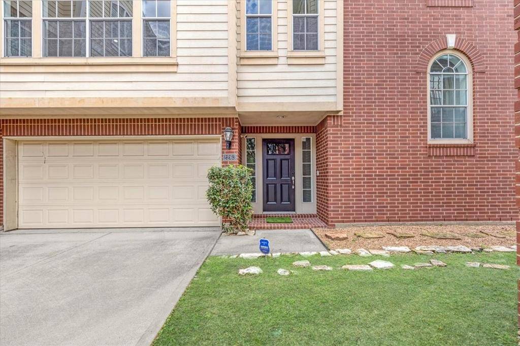 Charming close-up of the front entryway, with a rich black front door, manicured greenery, and brick-lined path welcoming you home.