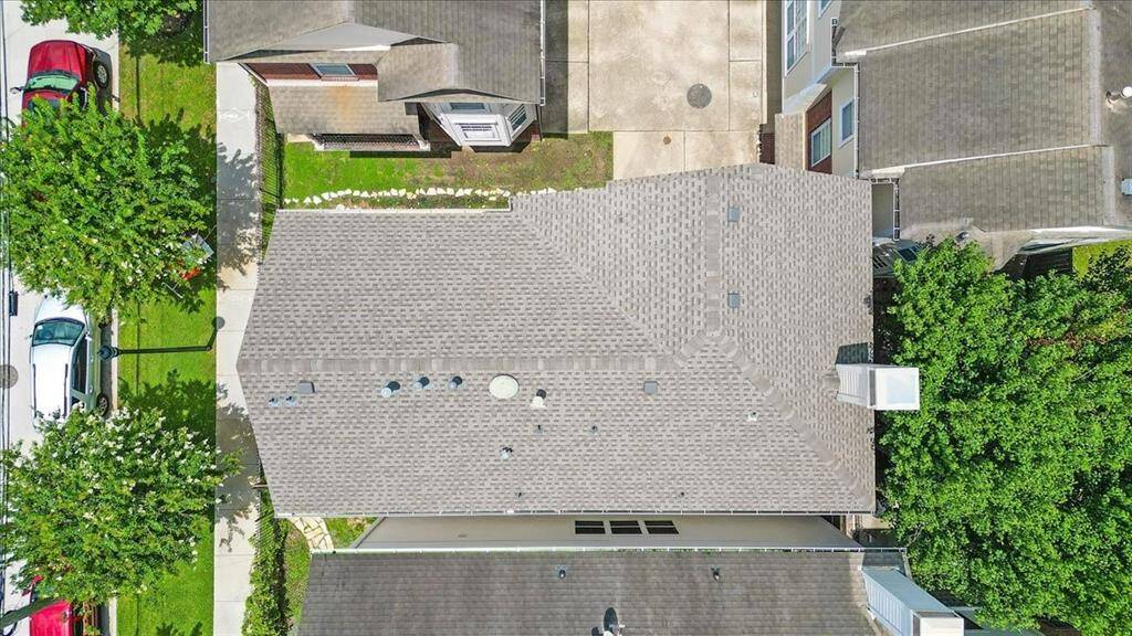 Bird’s-eye shot of the roofline and property footprint, emphasizing the structural layout and proximity to the landscaped pathway and drive.