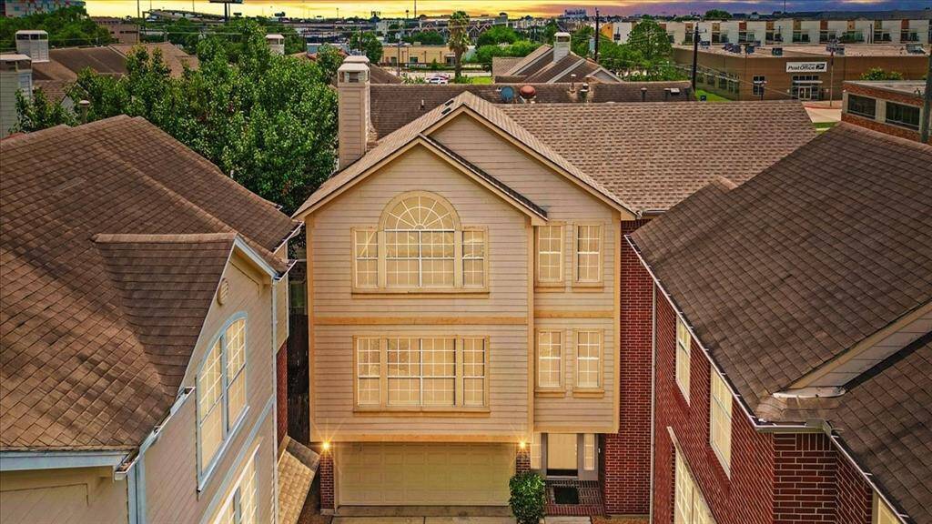 Stunning twilight view of the home’s façade, featuring a symmetrical design with large arched and grid windows that draw in natural light. The warm glow from inside highlights the inviting character of this multi-level home tucked in a cozy gated community just steps from Midtown's best.
