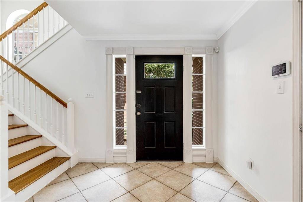 Bright and airy entry with tiled flooring, crown molding, and full-length sidelights flanking the black door—designed for a polished first impression.
