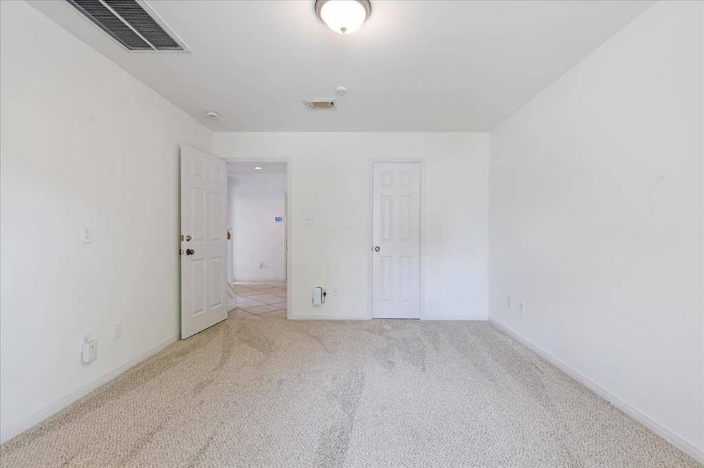 View from inside the first-floor bedroom showcasing the entry to the en-suite bathroom and spacious walk-in closet. Convenient private access to the outdoor patio makes this a standout space.