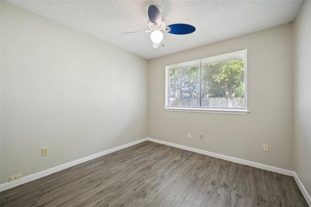 Bright and inviting guest bedroom with ample natural light and sleek hardwood flooring.