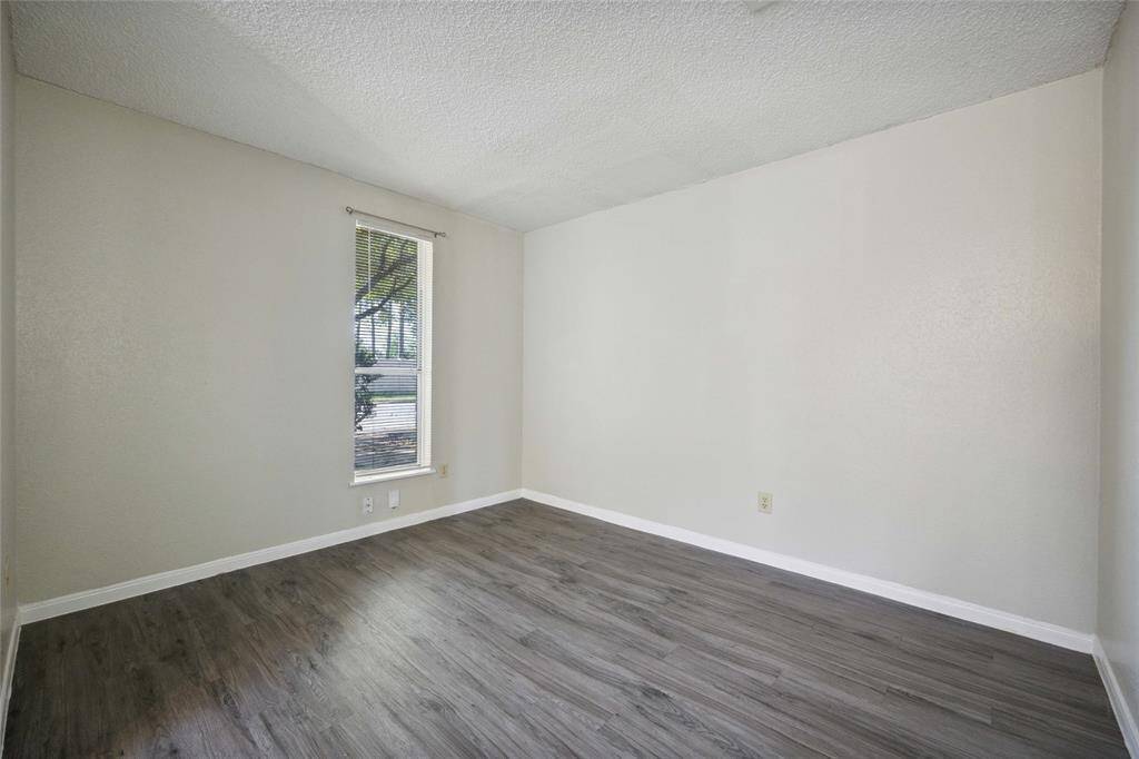 Inviting guest bedroom with natural light and sleek flooring, perfect for comfort and style.