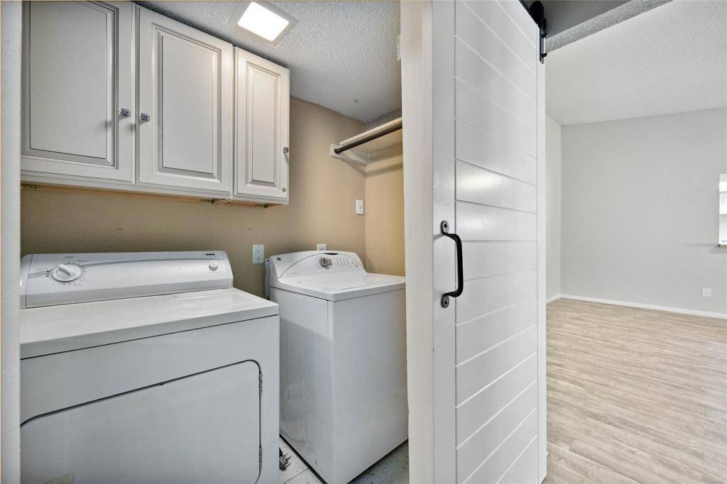 Convenient laundry area with cabinets, neatly concealed by sliding doors.