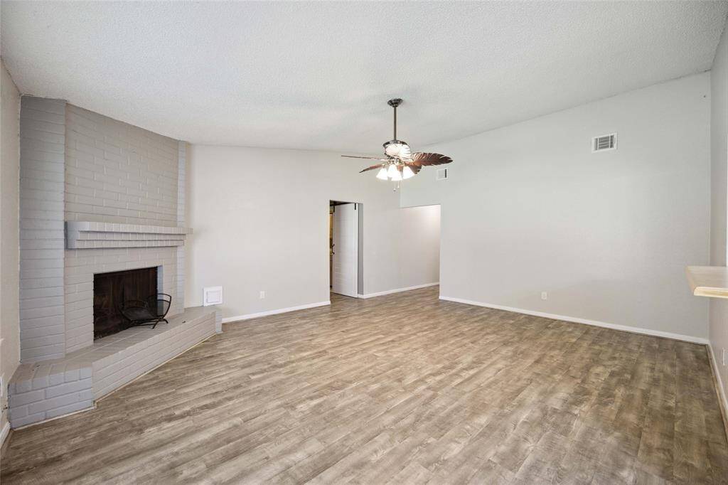 Spacious living room featuring elegant wood look vinyl flooring, a cozy fireplace, and ample natural light—perfect for relaxing and entertaining.