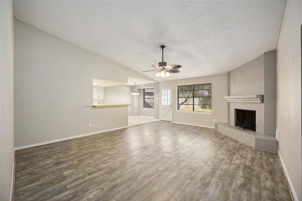 Spacious living room with elegant flooring, a cozy fireplace, and abundant natural light.