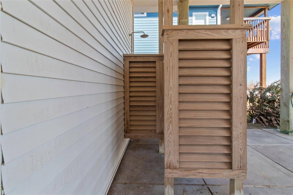 This image captures an outdoor shower with privacy screens, set against the backdrop of a cozy porch. Perfect for rinsing off after a day at the beach, this feature adds convenience and charm to your home.