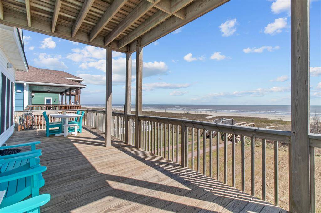 This photo showcases a beachfront home with a spacious covered deck offering stunning ocean views. The deck features comfortable seating, perfect for relaxing and enjoying the coastal scenery.