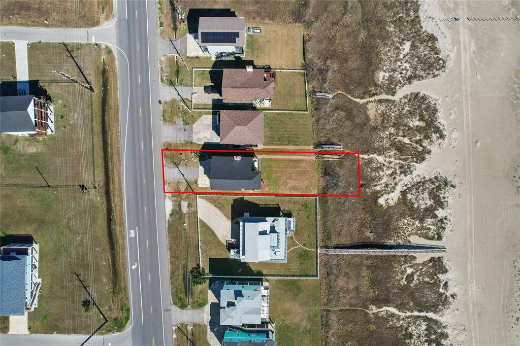 This aerial photo showcases a beachfront community with homes lining the coast. The view highlights the proximity to the ocean, offering potential for stunning sea views and easy beach access. The neighborhood is well-structured, featuring a mix of homes with spacious plots and clear road access.