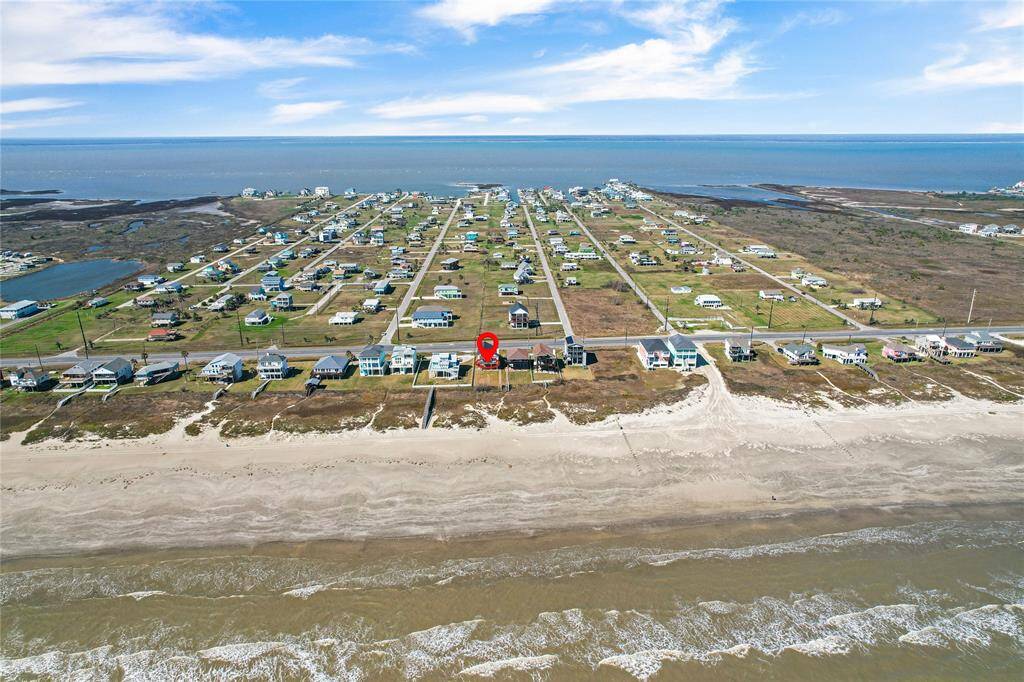 This photo showcases a row of beachside homes with direct access to a sandy shoreline. The properties are situated along a quiet road, offering picturesque ocean views and easy beach access, ideal for seaside living.